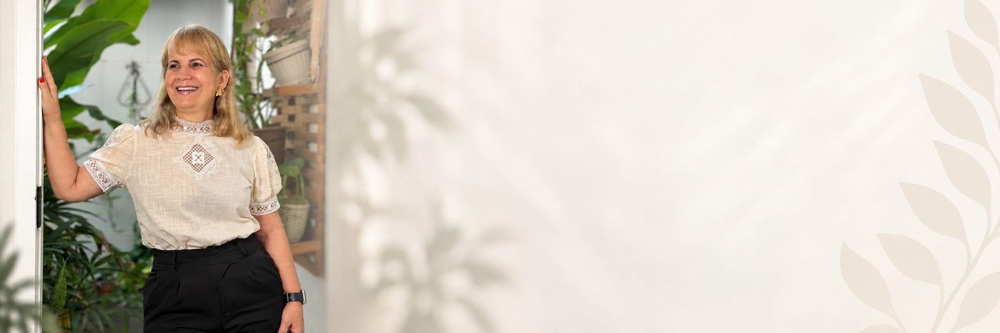 Liz Midlej sorrindo em um ambiente cheio de plantas
